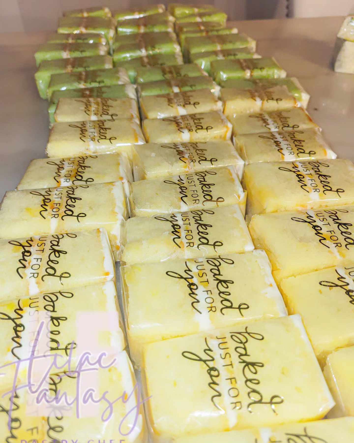 Multiple yellow and green individually cake slices wrapped in "baked just for you" by pastry chef Lilac